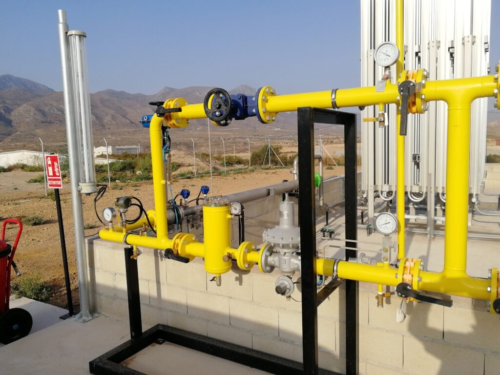Primer plano de colectores de acero, válvulas de seguridad y reguladores de presión en una instalación de gas de alta presión.